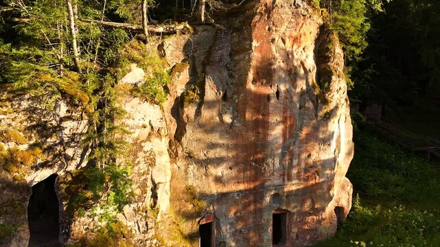 Devonian Red Sandstone Rock Cliffs Towering Above The Mystical Forest Of Gauja National Park In Ligatne, Latvia. Drone Slowly Rotating Down The Rock Wall.
