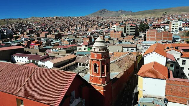 Aerial footage capturing a historic tower and hilly neighbourhood in Potosi, Bolivia, with stunning views of a mountain backdrop