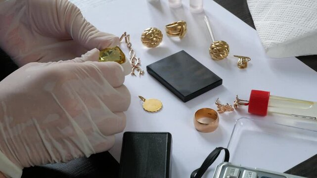 A pawn shop employee tests old gold jewelry using reagents and a touchstone, Buying old gold