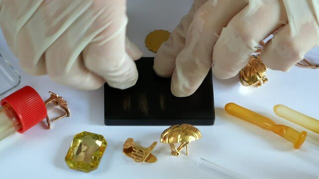 A pawn shop employee tests old gold jewelry using reagents and a touchstone, Buying old gold
