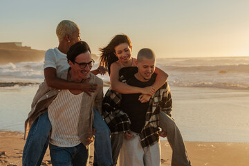 Friends giving piggyback rides on beach at sunset