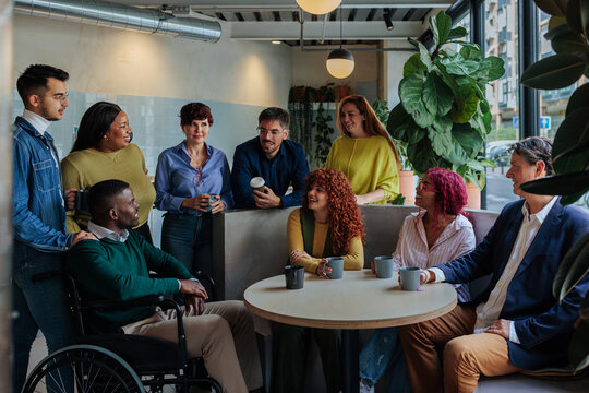 Diverse business team enjoying coffee break, discussing ideas in modern office space