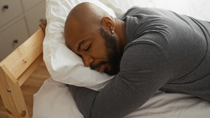 Handsome man resting on bed in cozy bedroom with natural light entering from window, displaying serene indoor ambiance