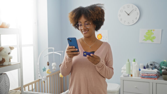 Woman standing in bedroom using phone and card near crib showcasing modern lifestyle and technology in home - Powered by Adobe