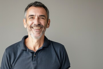 Fototapeta premium Portrait of a jovial man in his 40s wearing a sporty polo shirt isolated on blank studio backdrop