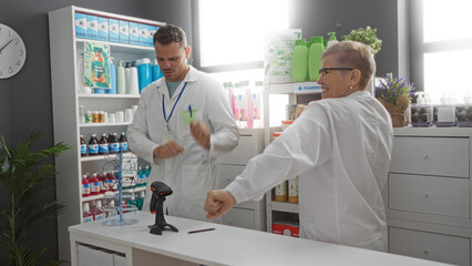 Obraz premium Woman and man pharmacists enjoying a light moment at the pharmacy counter filled with various health products.