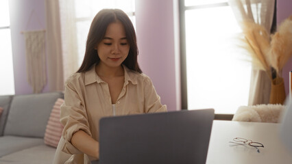 Woman working from home on a laptop while sitting comfortably in a living room with soft lighting and modern decor