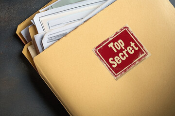 brown envelope with a red stamp that says Top Secret. The envelope is on a table