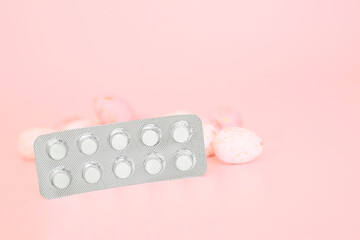 White medications in tablets, blisters, capsules on pink