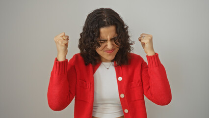 Young hispanic woman celebrating with a joyful expression, isolated over white background, wearing...