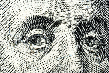 Close-up of engraved eyes from a dollar bill design.