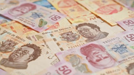 Obraz premium Colorful mexican banknotes scattered featuring various denominations of pesos with intricate designs and portraits of notable figures.