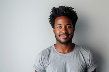 Fototapeta premium Portrait of a satisfied afro-american man in his 20s dressed in a casual t-shirt in front of plain white digital canvas