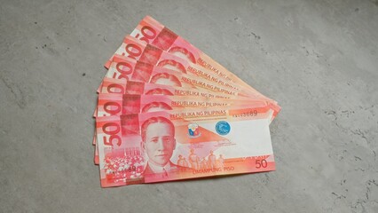 Philippine pesos banknotes fanned out on a gray concrete surface highlighting currency and economic theme.