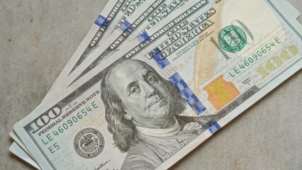 Closeup of several united states hundred dollar banknotes fanned out on a concrete surface