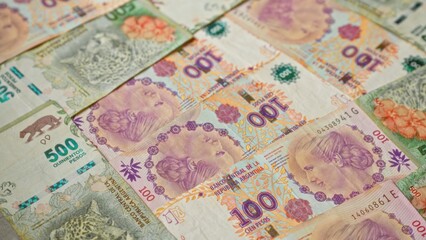 Fototapeta premium Argentinian pesos banknotes scattered on a flat surface showcasing different denominations and designs, highlighting the colorful currency of argentina.