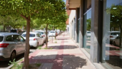 Tree-lined urban street with blurry, green trees, parked cars, and defocused buildings showcasing...
