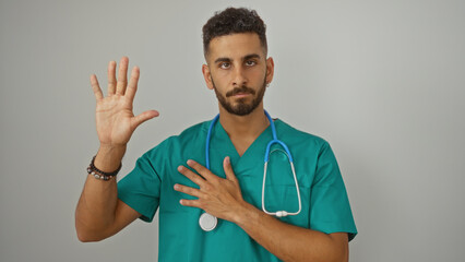 Handsome young hispanic man with a stethoscope over an isolated white background raising his hand...