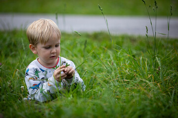 beautiful blond child playing on the ground appreciating nature
