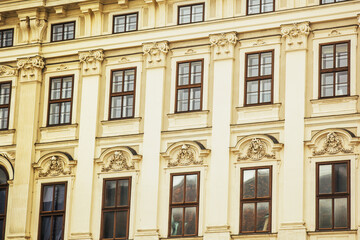 Fototapeta premium Vienna, Austria - May 12, 2019: Ancient architecture of residential buildings. Windows of beautiful palace with sculptures over the, closeup photo.