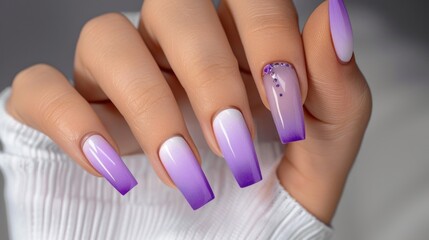 Hands of a woman with nails painted in purple gradient color, rectangular manicure, gel nail polish with french tip design and rhinestones. Close-up of beautiful hands on white background.