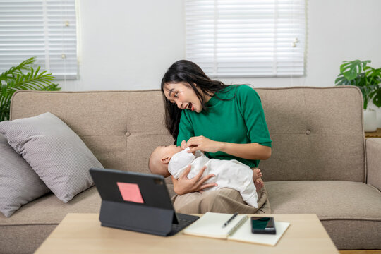Mother is taking care of her baby while working from home