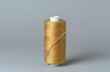 Brown bronze thread spool with needle close-up flat lay top view background with copy space for text