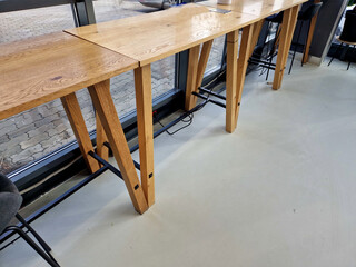 a work table with a network connection and an electrical outlet under a stainless steel cover. modern office with large windows and a wooden counter in a cafe with bar stools