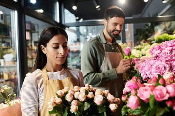 A husband and wife collaborate in their cozy florist shop surrounded by vibrant flowers.