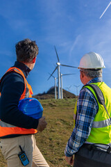 two Engineers inspecting wind turbines for green energy production