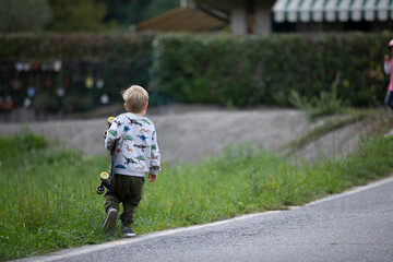 beautiful little and friendly blond boy playing on his skateboard