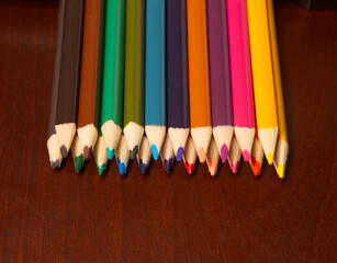 stacked colored pencils on wooden background