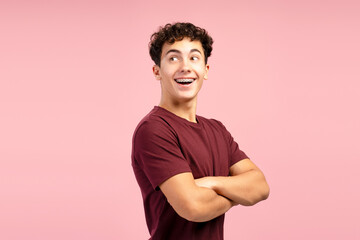 Excited, happy teenager boy with braces wearing red t shirt with crossed arms, looking away