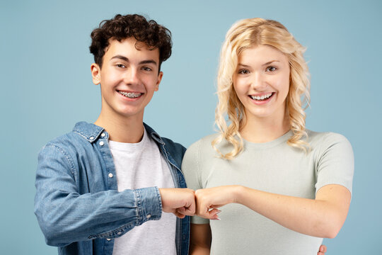 Smiling, positive teen boy and girl giving fist bump looking at camera. Deal, team, support concept