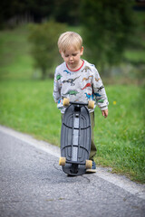 beautiful little and friendly blond boy playing on his skateboard