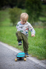 beautiful little and friendly blond boy playing on his skateboard