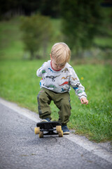 beautiful little and friendly blond boy playing on his skateboard
