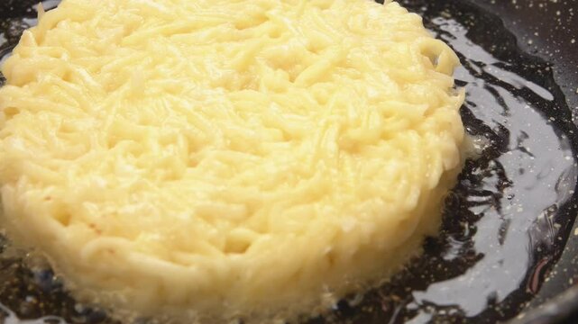 Close-up panorama of the fried potato pancake sizzling on the frying pan. Potato pancakes draniki recipe. High quality 4k footage