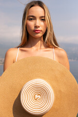 A woman is holding a straw hat with a white rim