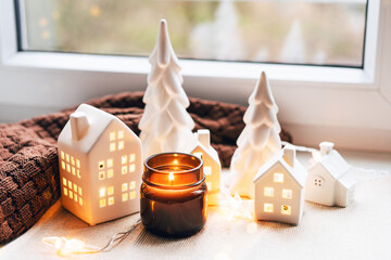Cozy Christmas Scene with Ceramic Houses and Candlelight by a Window