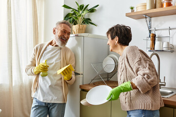 Happy couple shares laughter and warmth while cleaning up in their inviting kitchen space.