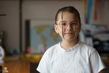 Little beautiful teenage girl in glasses with a hairstyle. Blurred children's room in the...