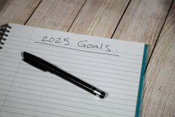 2025 goals written on lined paper notepad on wooden table