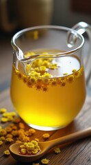 Fototapeta premium A clear glass pitcher of vibrant chamomile tea garnished with fresh chamomile flowers, set on a wooden table with a honey dipper nearby