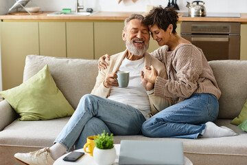 Couple enjoys a joyful moment together, sipping tea in their cozy living space.