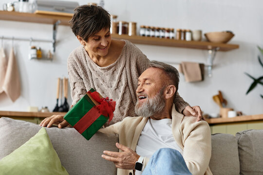 A couple shares a warm moment unwrapping a thoughtful gift in their cozy living room.