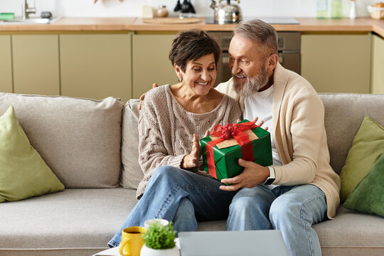A mature couple shares a heartfelt moment as they joyfully unwrap a gift together.