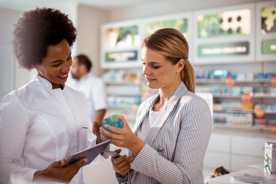 Pharmacist assisting woman with medication choice in pharmacy