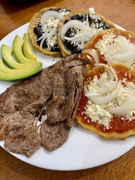 Platillo mexicano de carne asada servido con picadas veracruzanas de salsa roja y de frijol negro con cebolla y queso; acompa&ntilde;adas de rebanadas de aguacate