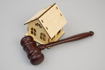 Judge gavel and house model on gray background.